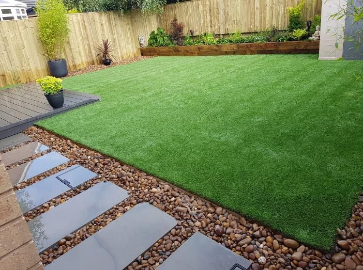 Artificial grass garden lawn with stone bordering and tiles.