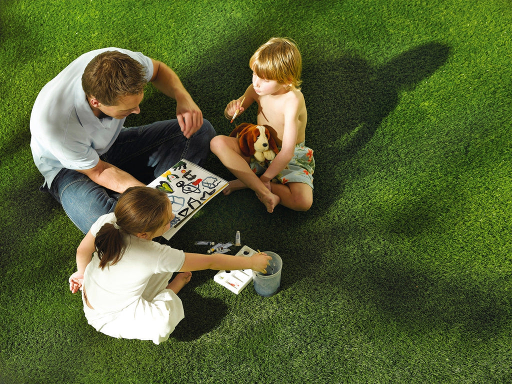 Father painting with son and daughter on an artificial grass lawn.