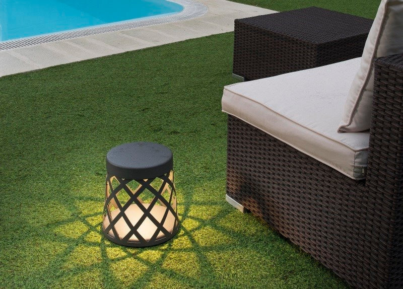 Outdoor lamp and garden chair on fake grass lawn by a poolside.