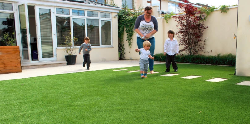 Mother playing on the grass in the garden with three children.