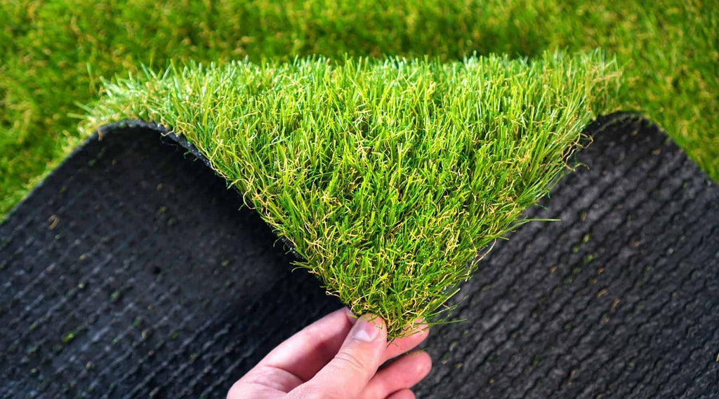 Hand folding back artificial turf backing to show green fibres.