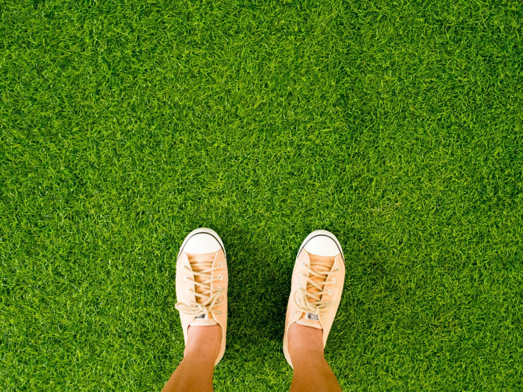 Feet in orange trainers on artificial grass.