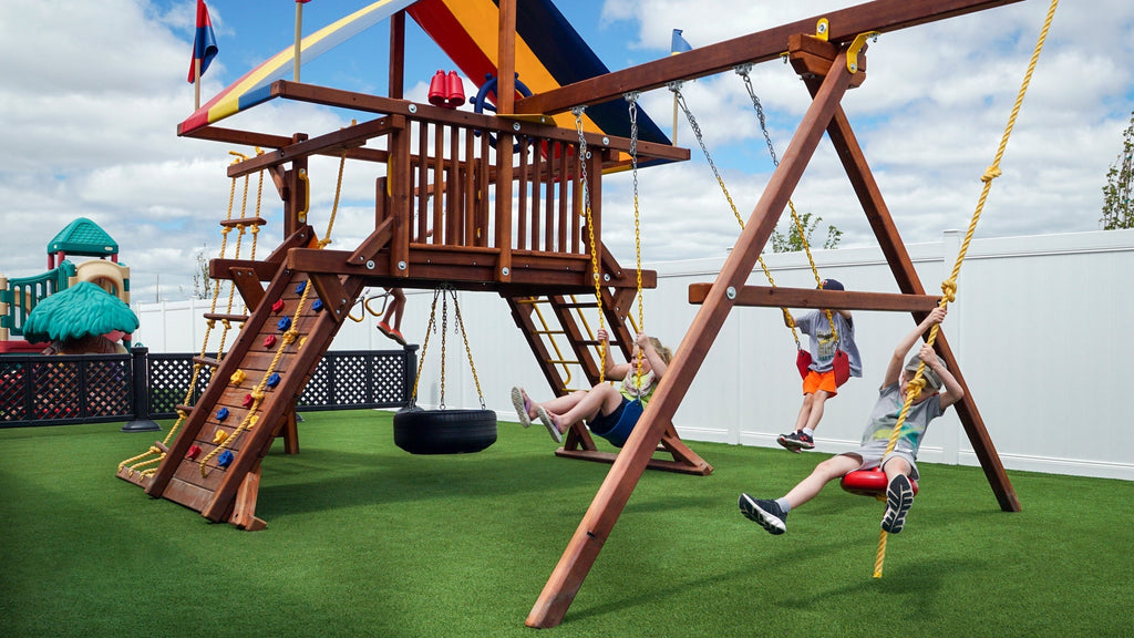 Children's play area with wooden swing set and artificial turf.